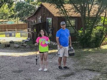 Image of a father and daughter leaving their lake cabin rental at Cedar Lodge to go to our private sandy beach and do some fishing!