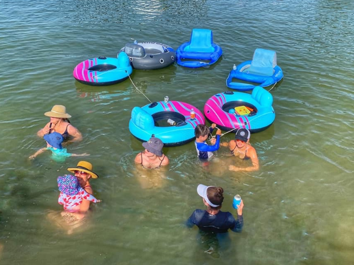 Image of guests and their floaties in the water at our private sandy lake beach